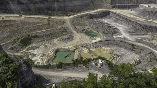 Aerial view of the active excavation floor of Vulcan Materials limestone quarry, featuring stepped walls, turquoise water pools, and machinery in Mt. Juliet, Tennessee, United States.