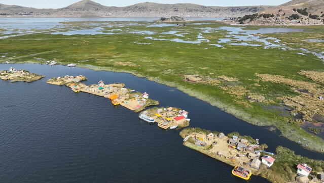Aerial view of the Uros floating islands on Lake Titicaca, featuring traditional reed structures, small boats, and surrounding wetlands in Urus, Peru.