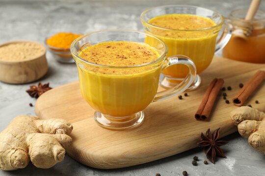 Golden milk turmeric latte and ingredients on grey table, closeup