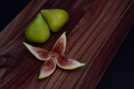 Fresh green figs and a sliced fig on a wooden board