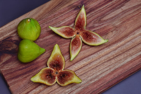 Fresh green figs whole and sliced on a wooden board, top view