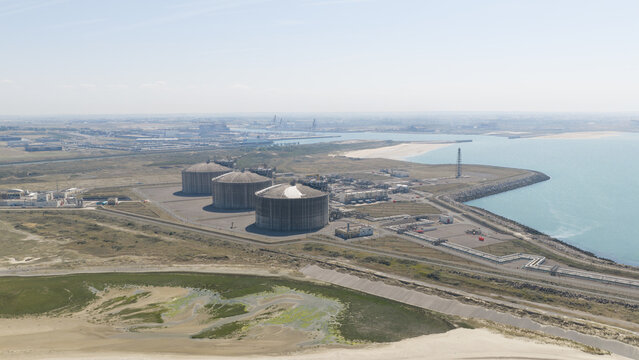 Aerial view of Dunkirk LNG Terminal with its large storage tanks and industrial infrastructure situated along the coastline in Loon-Plage, Hauts-de-France, France.