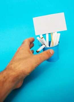 Cigarettes and lighter in a bucket on a blue background, stop smoking concept