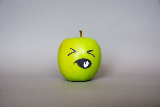 Funny green apple  Face  character with confused  expression on grey background. Abstract image of human emotions 