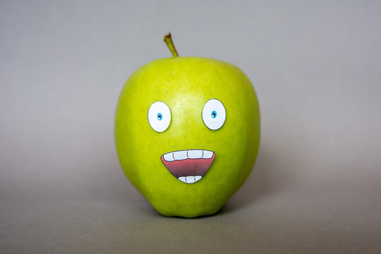 Funny green apple  Face  character with confused  expression on grey background. Abstract image of human emotions 