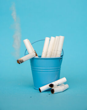 Cigarettes and lighter in a bucket on a blue background, stop smoking concept