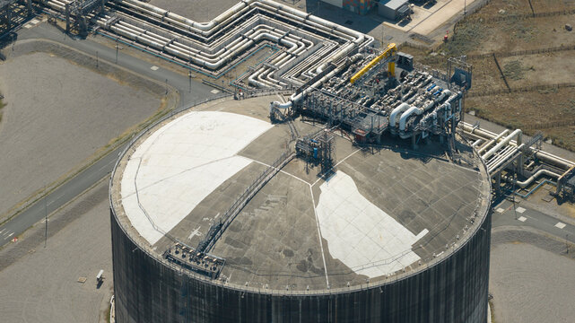 Aerial view of Dunkirk LNG Terminal featuring a large circular storage tank with complex piping systems and industrial infrastructure in Loon-Plage, Hauts-de-France, France.