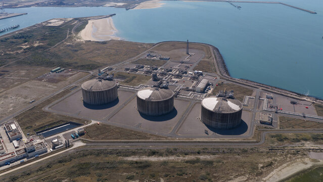 Aerial view of the Dunkirk LNG Terminal with its large circular storage tanks, industrial infrastructure, and coastal setting in Loon-Plage, Hauts-de-France, France.