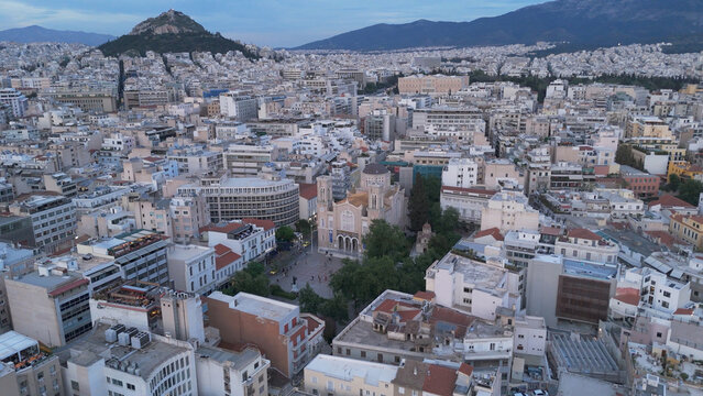Aerial view of the Metropolitan Cathedral of Athens surrounded by historic urban rooftops and buildings with Lycabettus Hill in the background in Athens, Greece.
