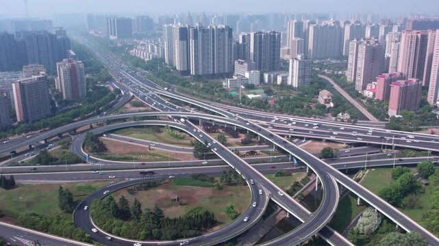 Aerial view of a complex urban highway interchange surrounded by high-rise residential buildings and green spaces.