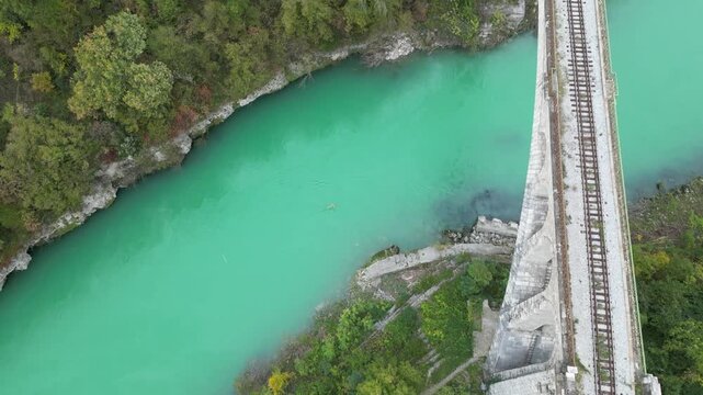 Stunning top down aerial shot flying over the famous Solkan Bridge, a stone arch railway bridge crossing the pristine turquoise Soca River