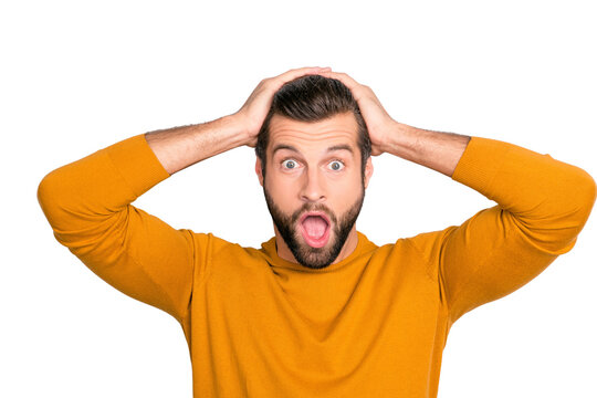 Close up portrait of shocked frustrated with open mouth holding head with hands with big eyes wearing bright yellow sweater isolated on gray background