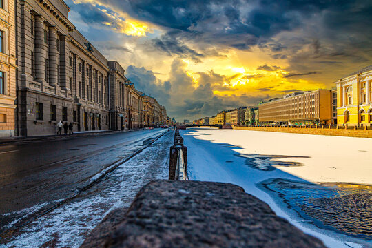 Snowy street glows under dramatic sunset skies