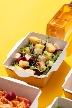 Healthy salad box with baked beetroot pineapple chunks feta cheese and microgreens on bright yellow background