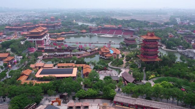 An aerial shot of a traditional Chinese architectural complex with lakes, towers and green landscapes.