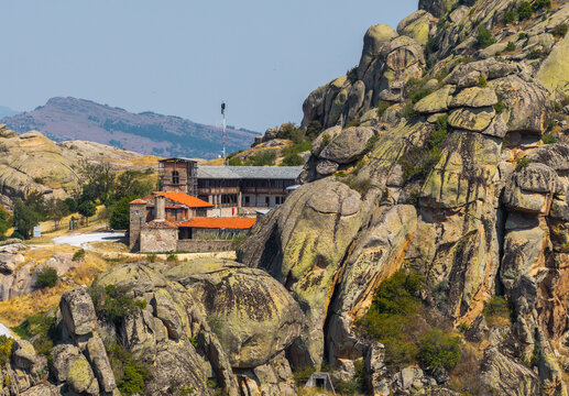 Aerial view of Treskavec Monastery with its orange-tiled roofs nestled among granite rock formations under a clear sky in Severna, Prilep Municipality, North Macedonia.