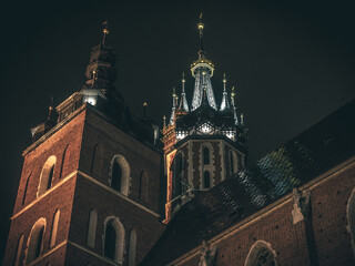 Oświetlone wieże Bazyliki Mariackiej w Krakowie z perspektywy żabiej nocą. Gotycka architektura sacralna, nocna iluminacja, dziedzictwo UNESCO, historia Polski i turystyka kulturowa. © Henryk Niestrój