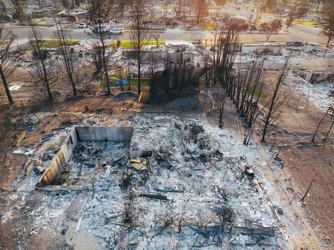 Aerial view of the aftermath of a wildfire showing charred residential structures, burnt trees, and ash-covered debris in a neighborhood in Spokane, Washington, United States.