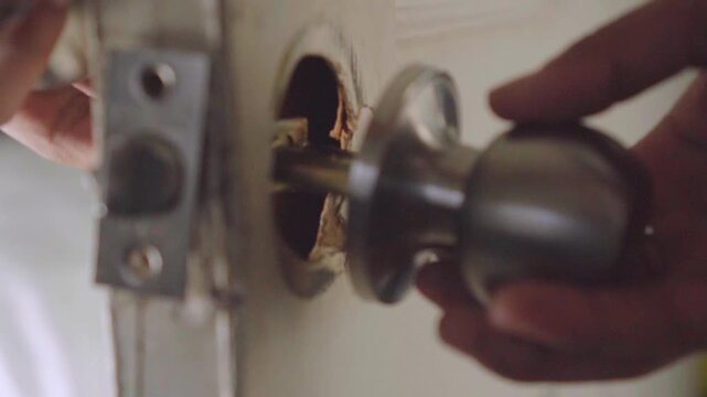 Handyman repairing and installing a doorknob mechanism