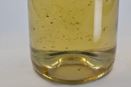 Wine sediment in bottle of white wine, closeup on white.