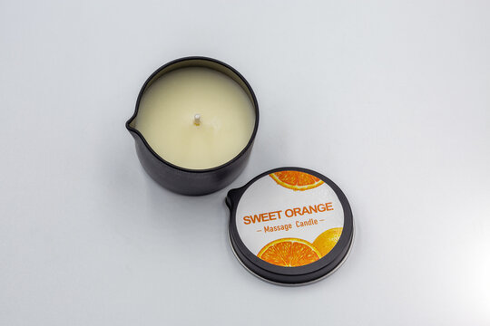 Sweet orange massage candle product closeup on white.