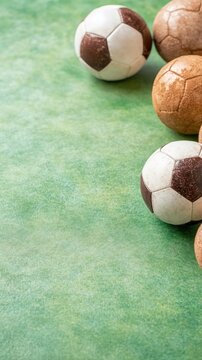 Collection of vintage soccer balls on a textured green background.