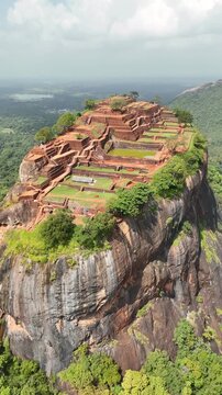 Aerial view of the ancient Sigiriya Lion Rock Fortress surrounded by lush tropical vegetation in central Sri Lanka, revealing the historic UNESCO World Heritage landscape, 4k.