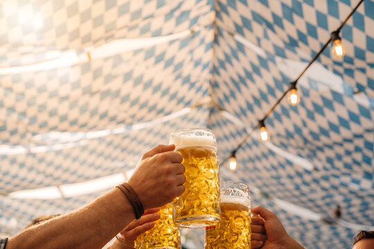 People Toasting Beer Steins Under Bavarian Checkered Festival Tent
