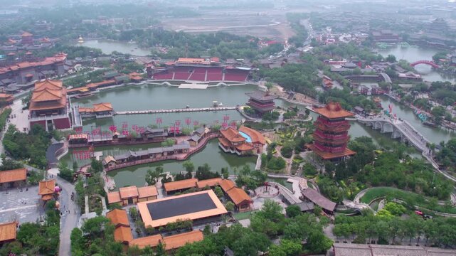 An aerial shot of a traditional Chinese-style scenic area with water systems, ancient buildings, towers and green spaces.