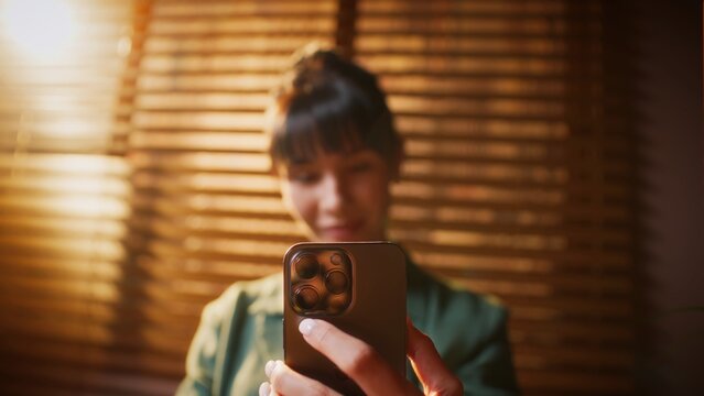 Young woman holding a smartphone and looking at the screen with a smile