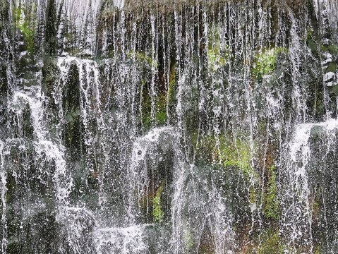 Beautiful waterfall with rocks and moss behind the water. Waterfall background.