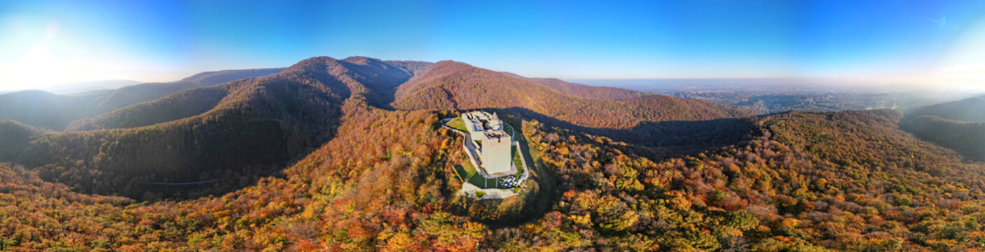 Aerial view of Medvedgrad fortress situated on a forested mountain ridge with autumn foliage under a clear blue sky in Zagreb, City of Zagreb, Croatia.