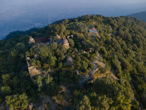 Aerial view of the ancient Tilla Jogian Archaeological Site, featuring historic stone ruins, domed structures, and lush greenery on a hilltop in Dina, Punjab, Pakistan.