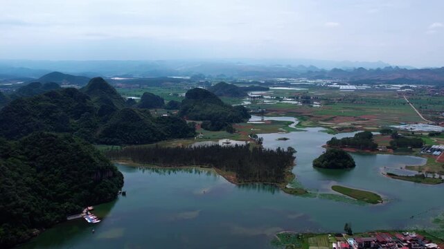 Aerial view of karst peaks surrounding wetland waters and farmland, forming a natural rural landscape.