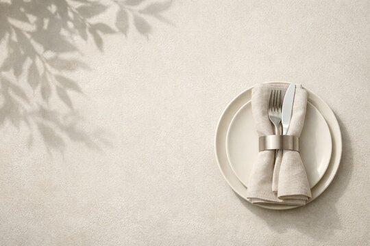 Minimal beige table setting with plate fork and knife on linen napkin for elegant dinner background and menu design
