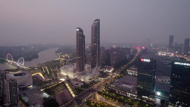 A twilight city panorama featuring twin skyscrapers, a river, and illuminated urban buildings in a modern metropolis.