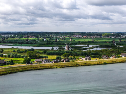 Aerial view of the historic Kinderdijk windmills, a UNESCO World Heritage site, set amidst lush green polders, waterways, and traditional houses in Kinderdijk, Zuid-Holland, Netherlands.