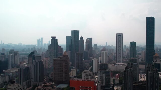 A high-angle view of a dense urban skyline filled with various tall buildings under a hazy sky.