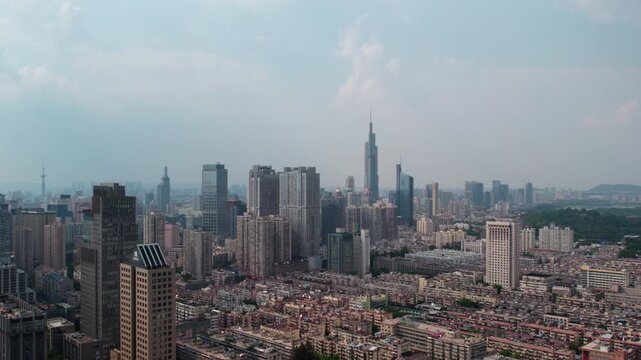 A high-angle panoramic shot of a dense modern urban city skyline with mixed high-rise and mid-rise buildings under a pale sky.