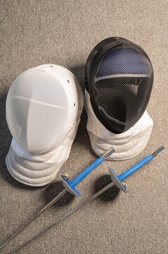 Fencing equipment. Swords and masks on the gray floor.