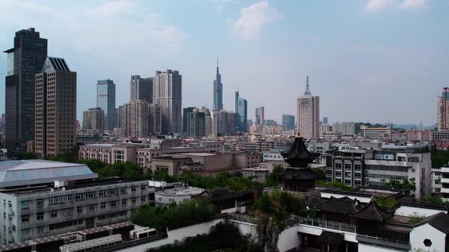 A panoramic city view combining modern high-rise skyscrapers and traditional low-rise buildings under a clear daytime sky.