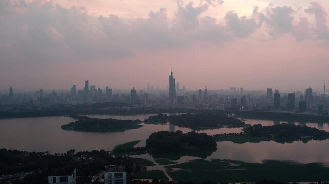 A panoramic view of a distant urban skyline across a calm lake, taken at twilight with soft atmospheric haze.