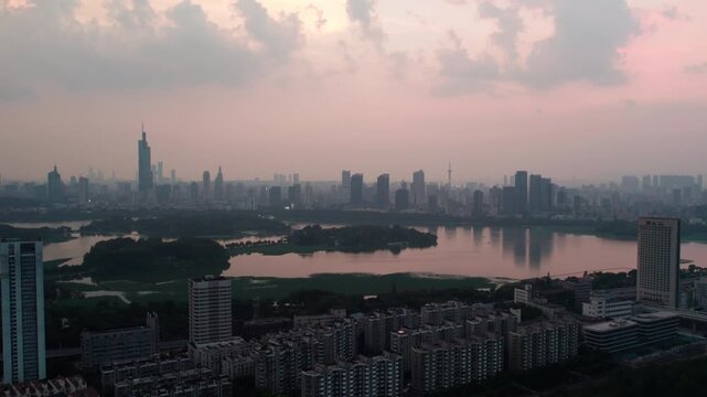 A panoramic urban landscape featuring a large lake with islands, surrounded by city buildings at twilight.