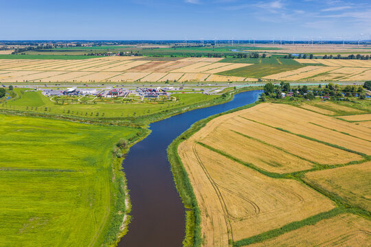 Aerial view of Droga Ekspresowa S7 highway winding through agricultural fields and meadows near a river in Nowy Dwor Gdanski, Pomeranian Voivodeship, Poland.