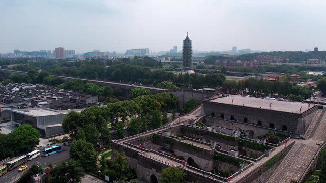 High-angle aerial shot of ancient city wall, historic pagoda, and surrounding urban green space on a clear day.