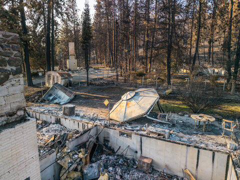 Aerial view of wildfire damage showing charred trees and destroyed structures in a residential area of Spokane, Washington, United States.