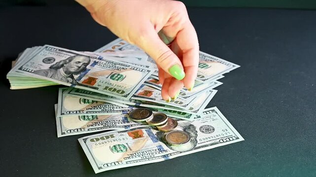 Footage of hands counting and spreading US hundred dollar bills with coins on a dark table a creative clip of money cash wealth and finance.