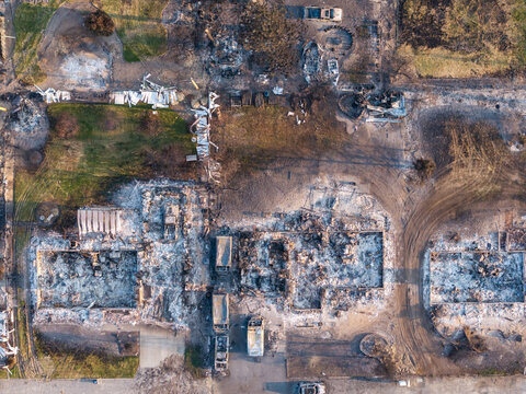 Aerial view of the aftermath of a wildfire showing destroyed residential homes with charred foundations and debris scattered across the landscape in Spokane, Washington, United States.