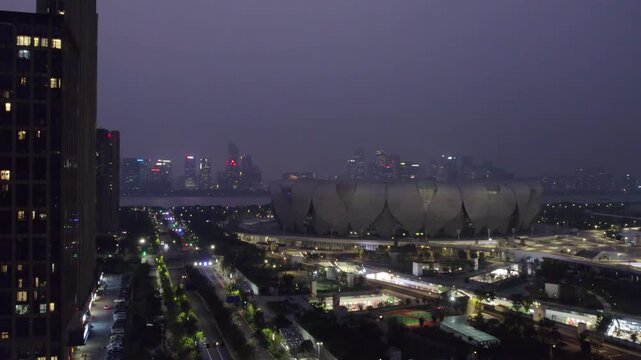 A wide night view of an urban area featuring a large stadium and surrounding high-rise buildings with illuminated streets.