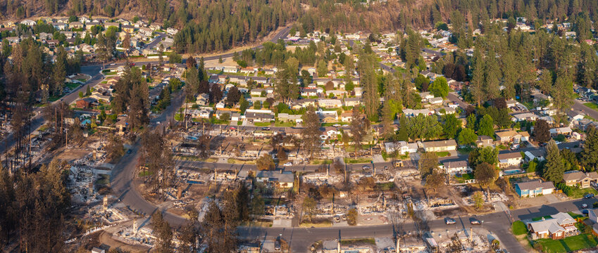 Aerial view of wildfire damage at Rifle Club Court and Nine Mile Road in Spokane, Washington, with a burned neighborhood beside nearby homes left standing.